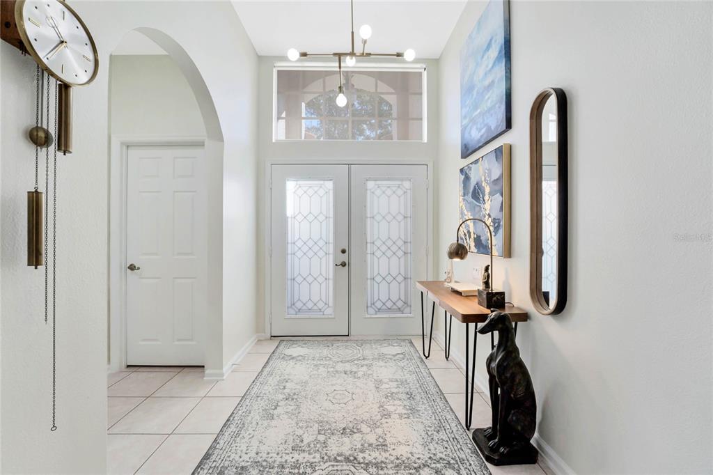 A bright entryway features a double front door, a runner rug, and a console table — 4713 WINDSOR AVENUE, ORLANDO, FL