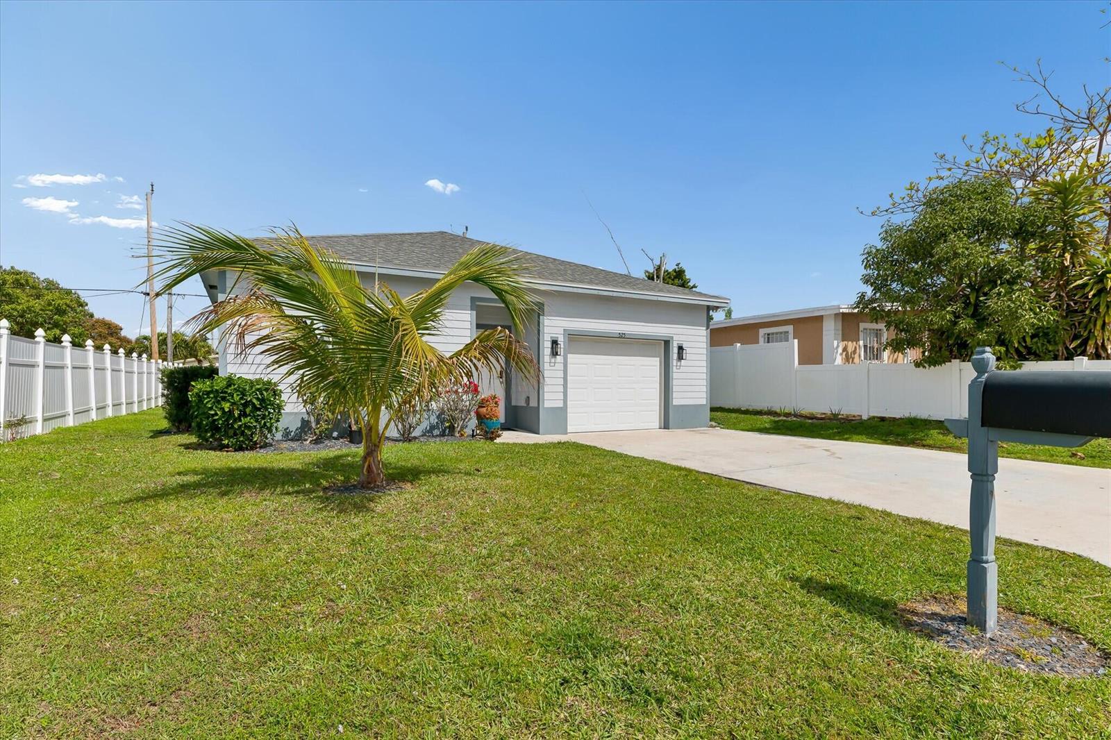 A single-story house with a white garage, gray siding, and a palm tree in the yard — 525 NW 12th Avenue, Boynton Beach FL 33435, BOYNTON BEACH, FL