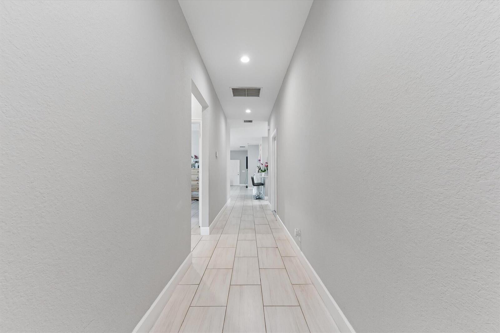A long, narrow hallway features light gray walls, recessed lighting, and light-colored rectangular floor tiles — 525 NW 12th Avenue, Boynton Beach FL 33435, BOYNTON BEACH, FL