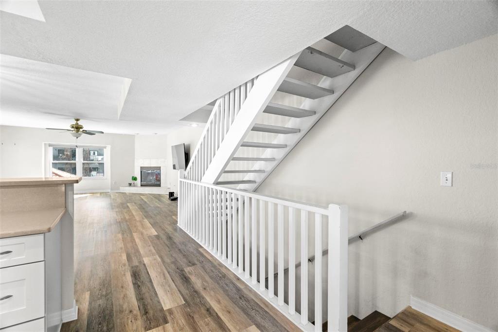 A staircase with white railings leads upward in a room with wood-look flooring — 545 PINELLAS BAYWAY S UNIT 207, TIERRA VERDE, FL