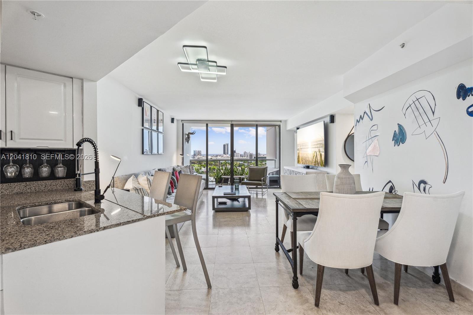 A modern open-concept living and dining area features tile floors, granite countertops, and balcony views — 1900 Sunset Harbour Dr # 1715, Miami Beach FL 33139, MIAMI BEACH, FL