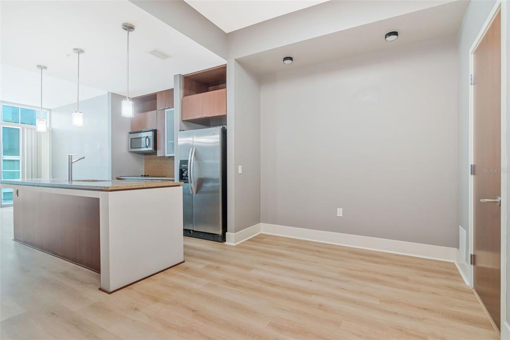 A kitchen with a breakfast bar, stainless steel refrigerator, and light wood-look flooring — 111 N 12TH STREET UNIT 1820, TAMPA, FL