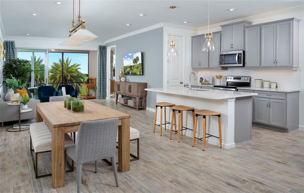 An open-concept kitchen and dining area features gray cabinets, a white island, and wood-look flooring — 11910 MANDALA COURT, VENICE, FL
