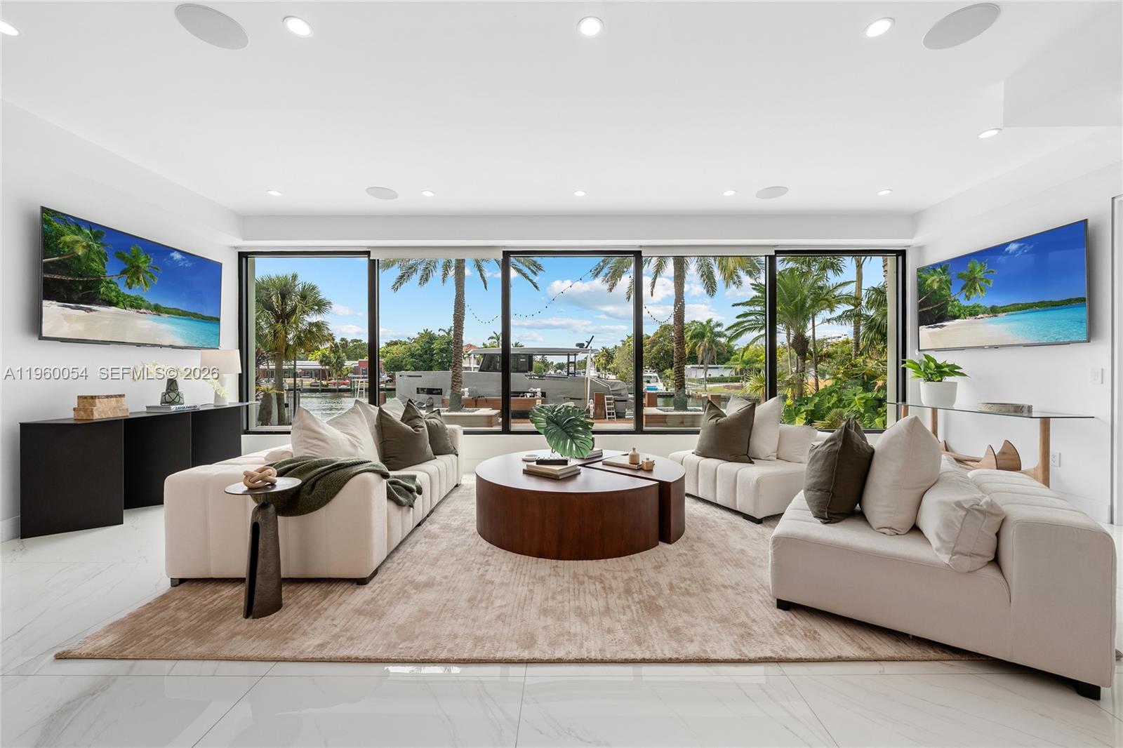 A modern living room features white furniture, a circular coffee table, and large floor-to-ceiling windows — 12880 N Bayshore Dr, North Miami FL 33181, NORTH MIAMI, FL