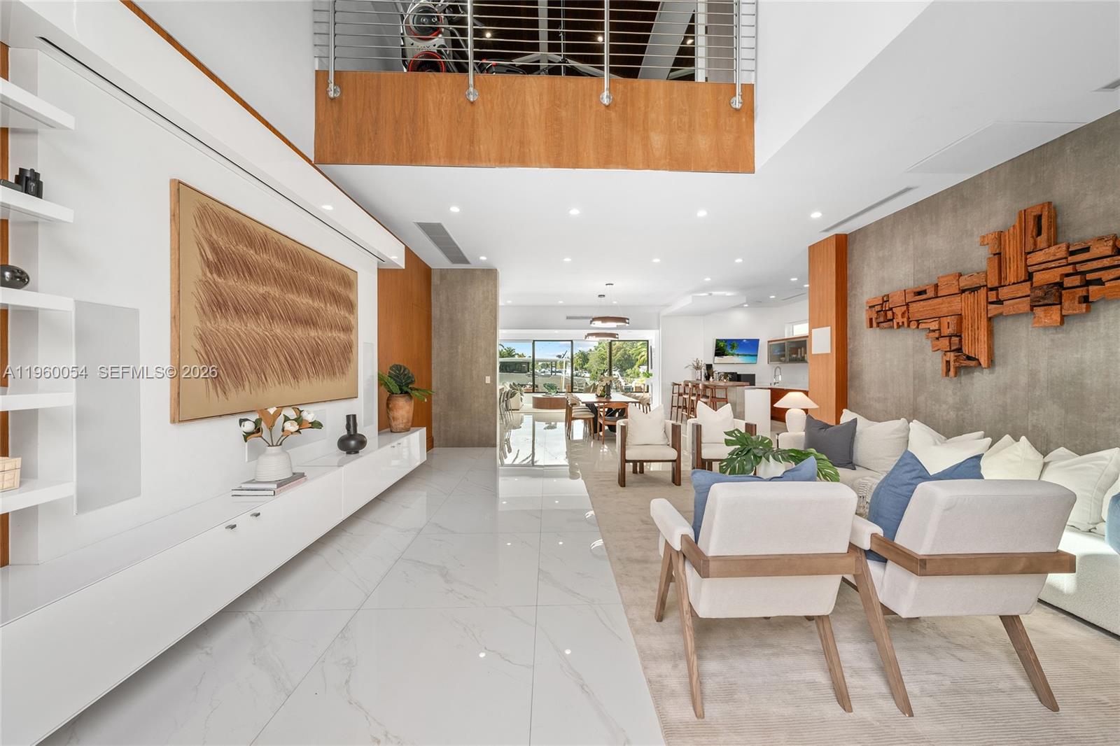 A modern living room features white tile floors, plush seating, and floor-to-ceiling windows overlooking water — 12880 N Bayshore Dr, North Miami FL 33181, NORTH MIAMI, FL
