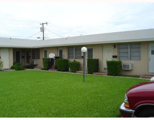 A single-story apartment building with a grassy lawn and a parked red vehicle — 7624 Pembroke Road # C, Miramar FL 33023, MIRAMAR, FL