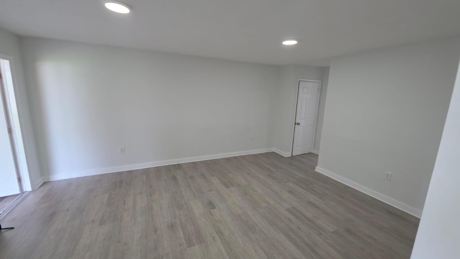 An empty room with light gray walls, wood-look flooring, recessed lighting, and a white door — 7624 Pembroke Road # C, Miramar FL 33023, MIRAMAR, FL