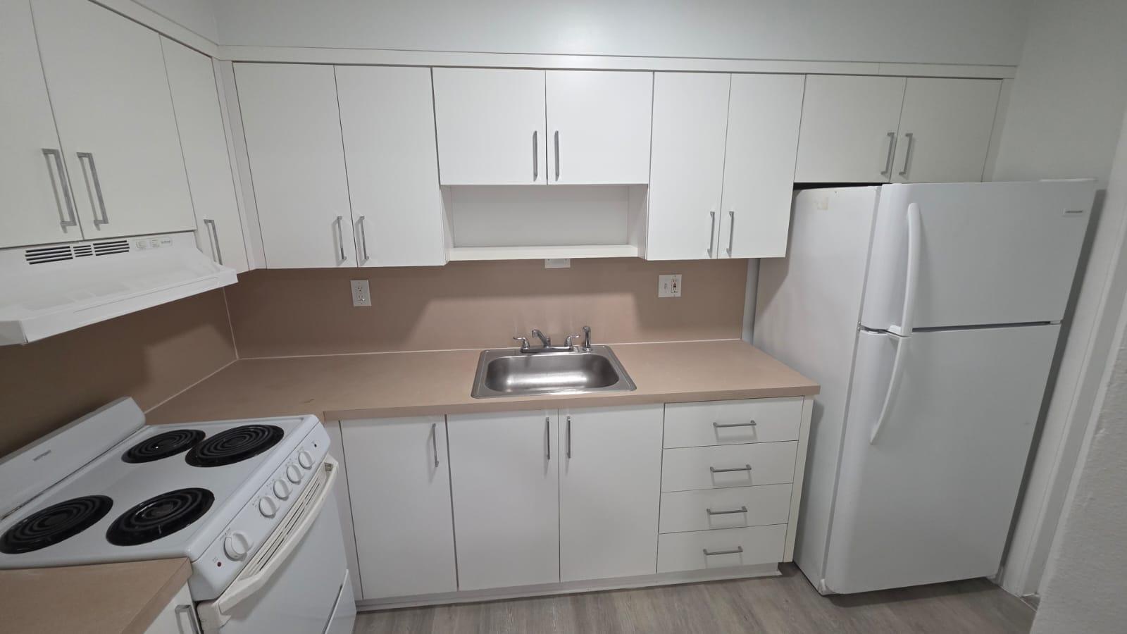 A kitchen features white cabinets, a beige countertop, a stainless steel sink, and white appliances — 7624 Pembroke Road # C, Miramar FL 33023, MIRAMAR, FL