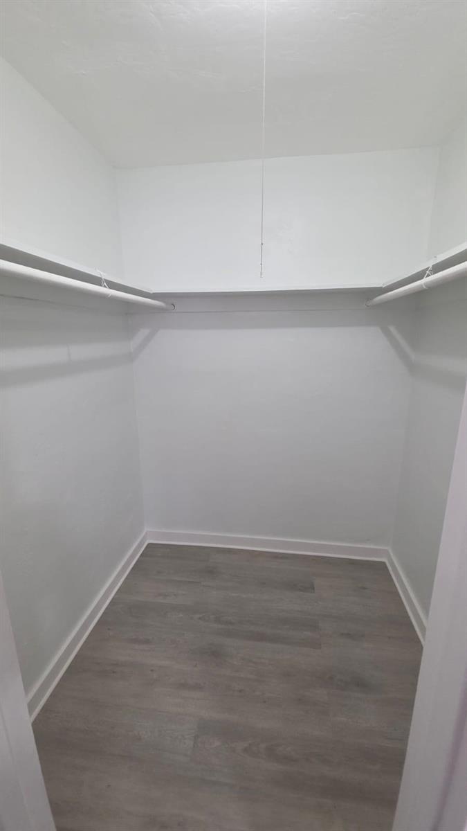 A walk-in closet with white walls, a top shelf, a hanging rod, and gray flooring — 7624 Pembroke Road # C, Miramar FL 33023, MIRAMAR, FL