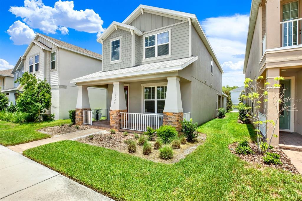 A two-story house with a front porch, stone pillars, and a gray siding exterior — 13729 RANGELAND BOULEVARD, ODESSA, FL