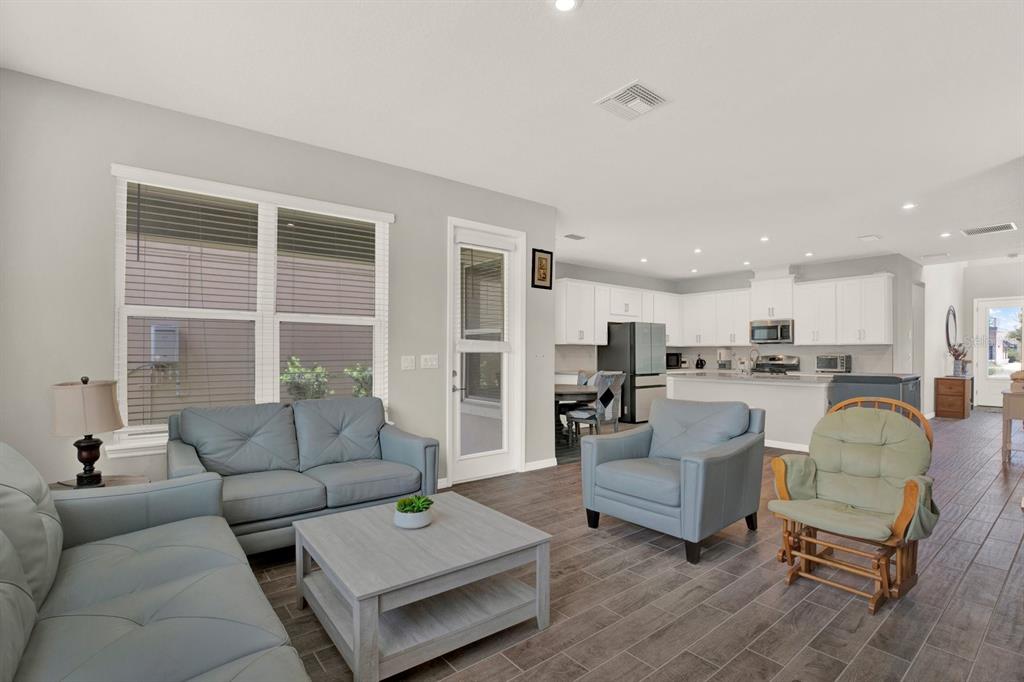An open-concept living room with light blue furniture, a wooden coffee table, and a kitchen — 13729 RANGELAND BOULEVARD, ODESSA, FL