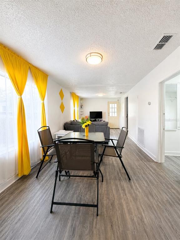 A dining area with a table and chairs opens into a living room with gray flooring — 1239 AVENUE K, HAINES CITY, FL