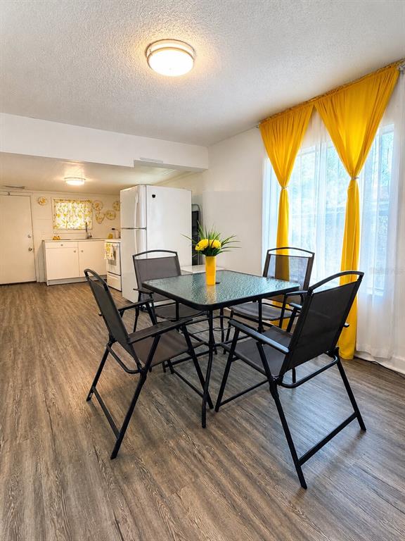 A dining area with a glass table, four chairs, and yellow curtains near a kitchen — 1239 AVENUE K, HAINES CITY, FL