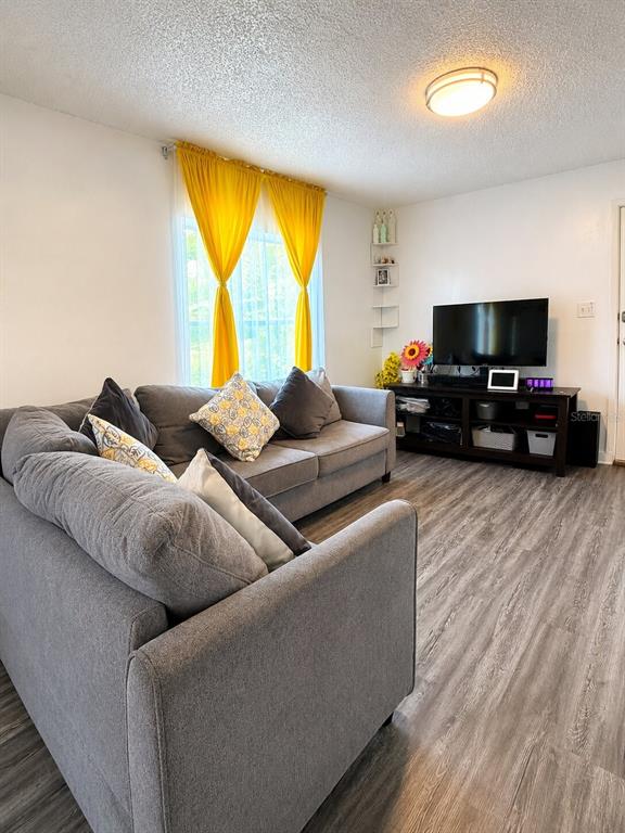 A living room features a gray sectional sofa, yellow curtains, and a dark wood media console — 1239 AVENUE K, HAINES CITY, FL