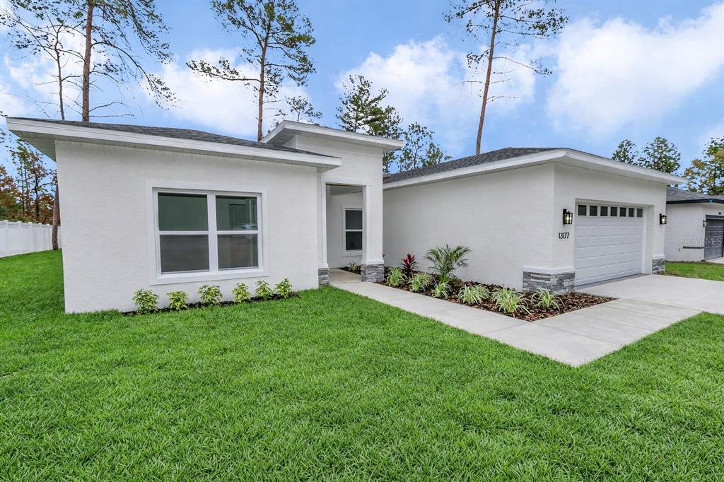 A white, single-story house with a garage, a front walkway, and a landscaped garden bed — 13177 SW 67TH AVENUE, OCALA, FL