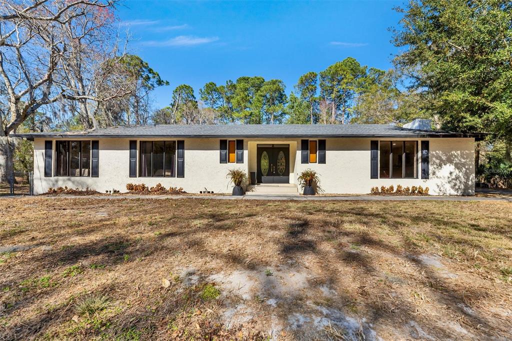 A single-story house with a light-colored stucco exterior, dark shutters, and a central double door — 7569 PARK CITY DRIVE, JACKSONVILLE, FL