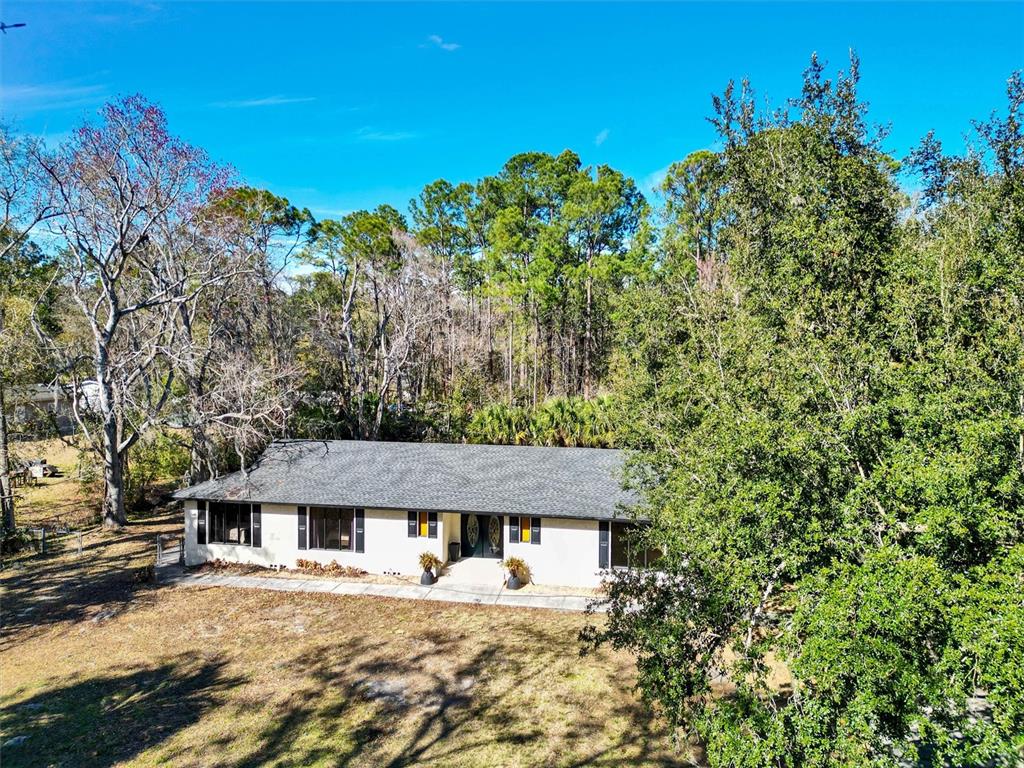 A single-story house with a light-colored exterior sits on a lot surrounded by trees — 7569 PARK CITY DRIVE, JACKSONVILLE, FL