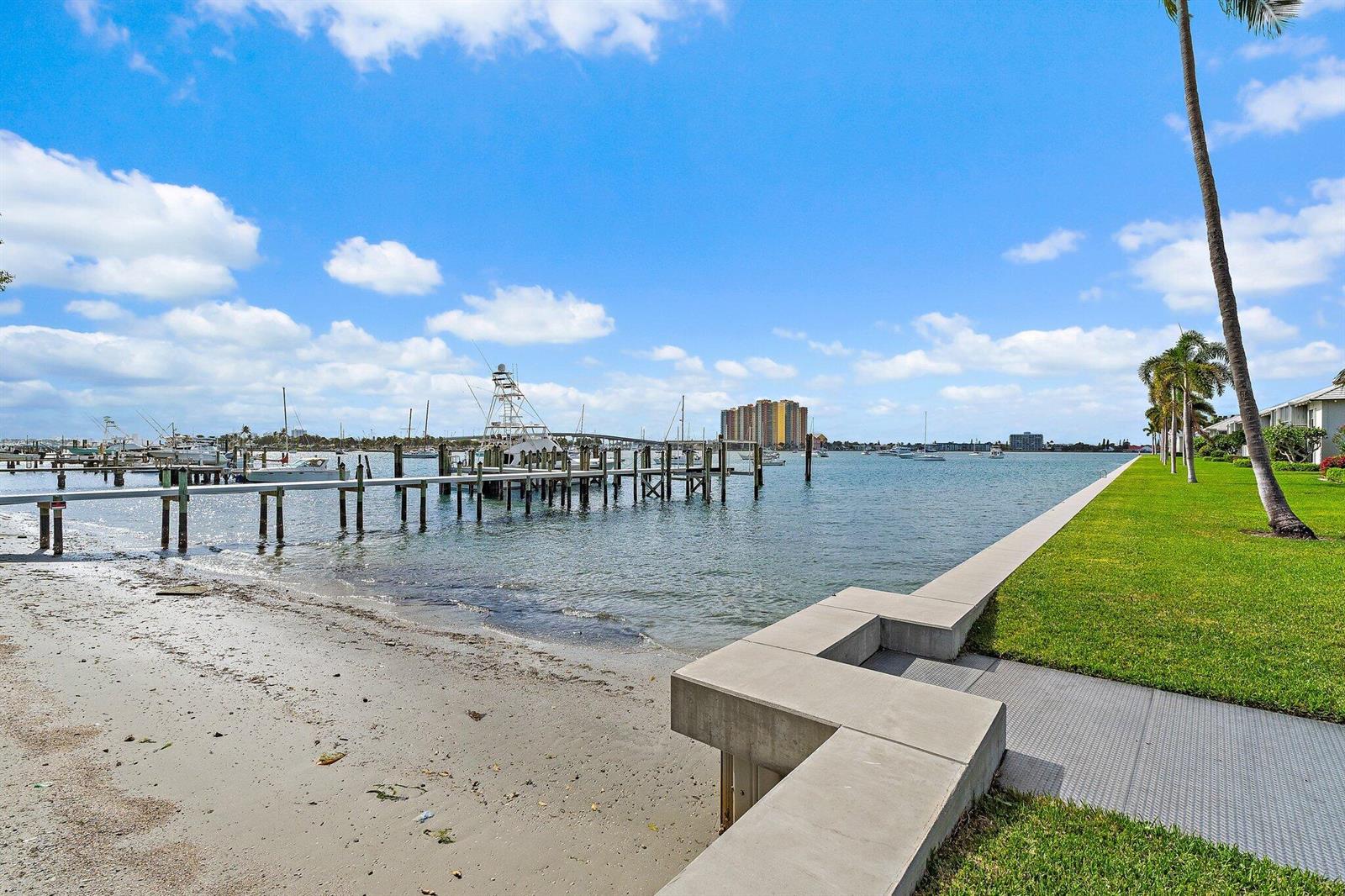 A concrete seawall borders a grassy lawn next to a sandy beach and boat docks — 1145 Sugar Sands Boulevard, Singer Island FL 33404, SINGER ISLAND, FL