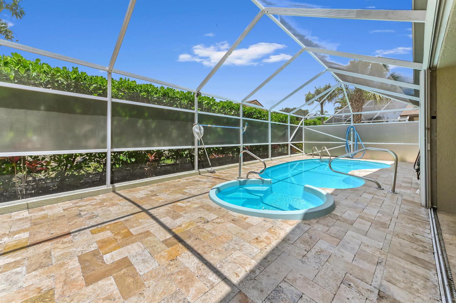 A screened-in patio features a swimming pool with a spa and stone paver flooring — 1163 Peninsula Way, FL 33413, FL