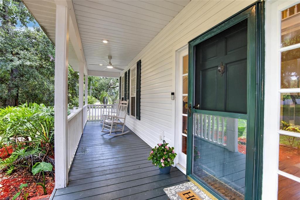 A covered front porch features a dark wooden floor, white railings, and two rocking chairs — 1701 COTTAGE OAKS COURT, BRANDON, FL