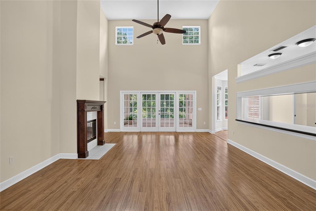 A living room with high ceilings, wood flooring, a fireplace, and glass doors to the outside — 1701 COTTAGE OAKS COURT, BRANDON, FL