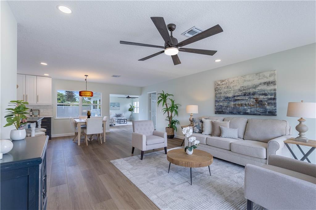 An open-concept living and dining area features light wood flooring, a ceiling fan, and furniture — SEBASTIAN, FL