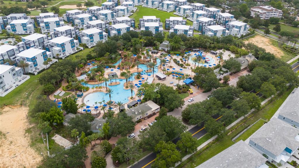 An aerial view shows a large resort swimming pool complex surrounded by multi-story residential buildings — 7740 SANDY RIDGE DRIVE UNIT 131, REUNION, FL