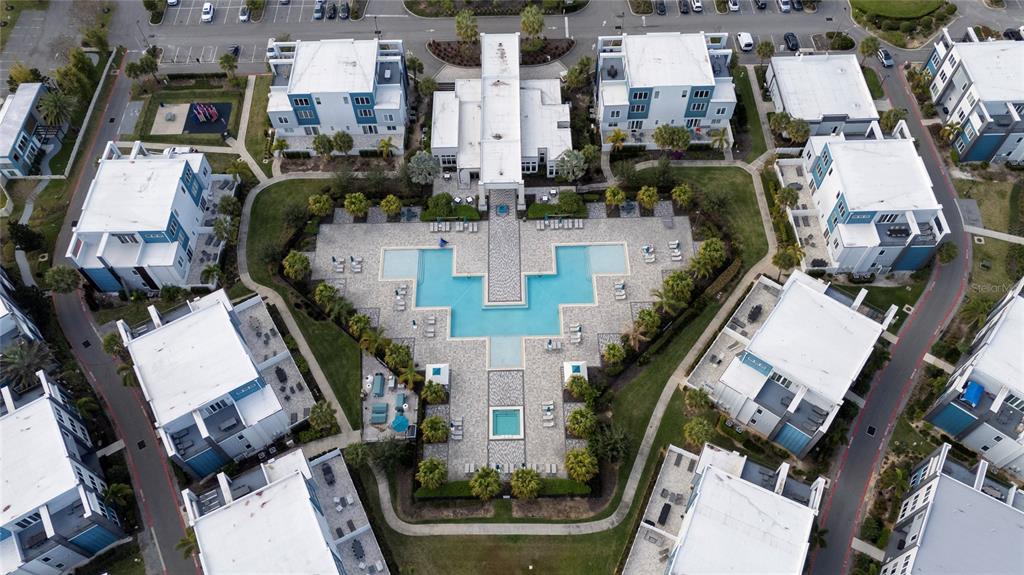 Aerial view of a residential complex featuring a central swimming pool and surrounding apartment buildings — 7740 SANDY RIDGE DRIVE UNIT 131, REUNION, FL