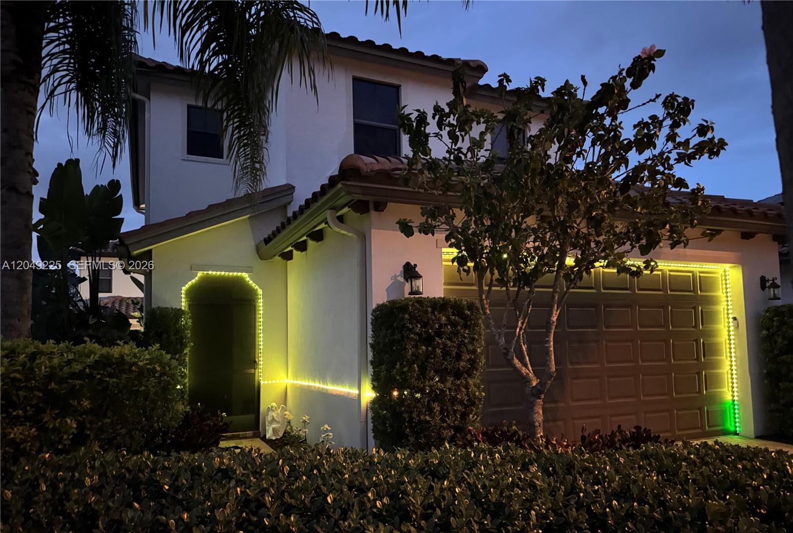 A covered entryway features a brown door, a bistro set, and a decorative bicycle wall art — 5434 USEPPA DR, Ave Maria FL 34142, AVE MARIA, FL