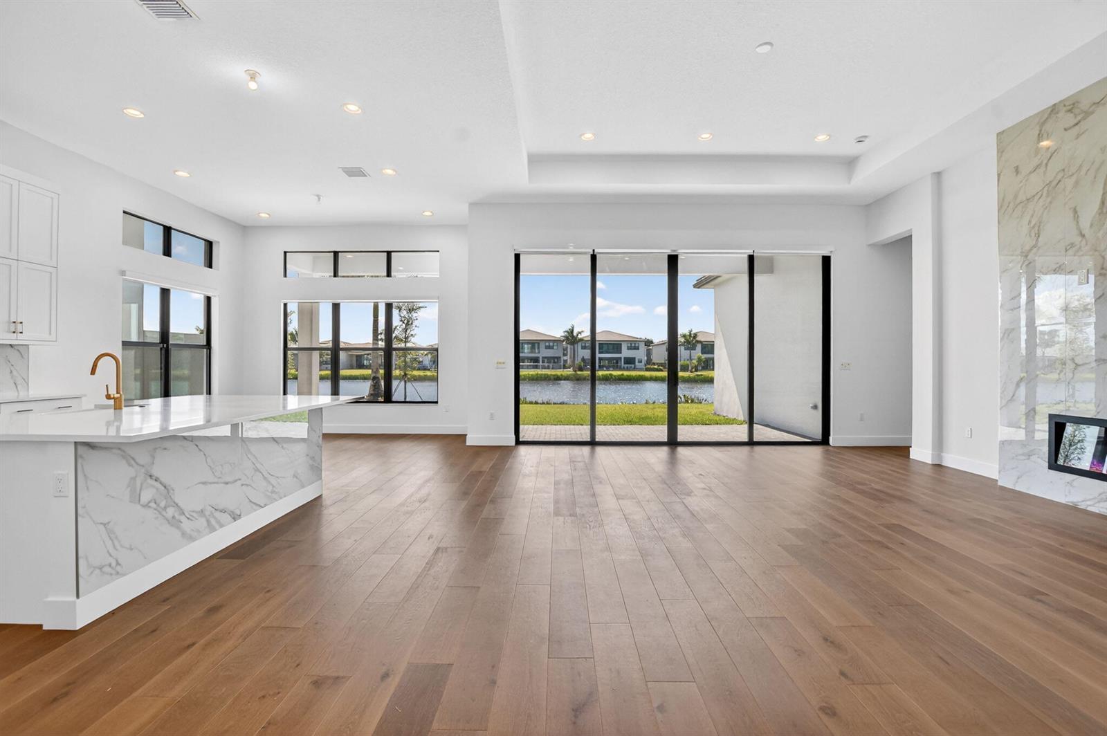 An open-concept living area features wood floors, a marble-topped kitchen island, and large sliding doors — 20041 Pacific Dunes Drive, Boca Raton FL 33434, BOCA RATON, FL
