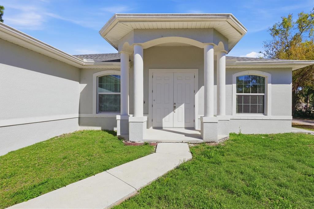A light-colored house exterior features a covered entryway with two white columns and double doors — 3498 DUNKIRK STREET, PUNTA GORDA, FL