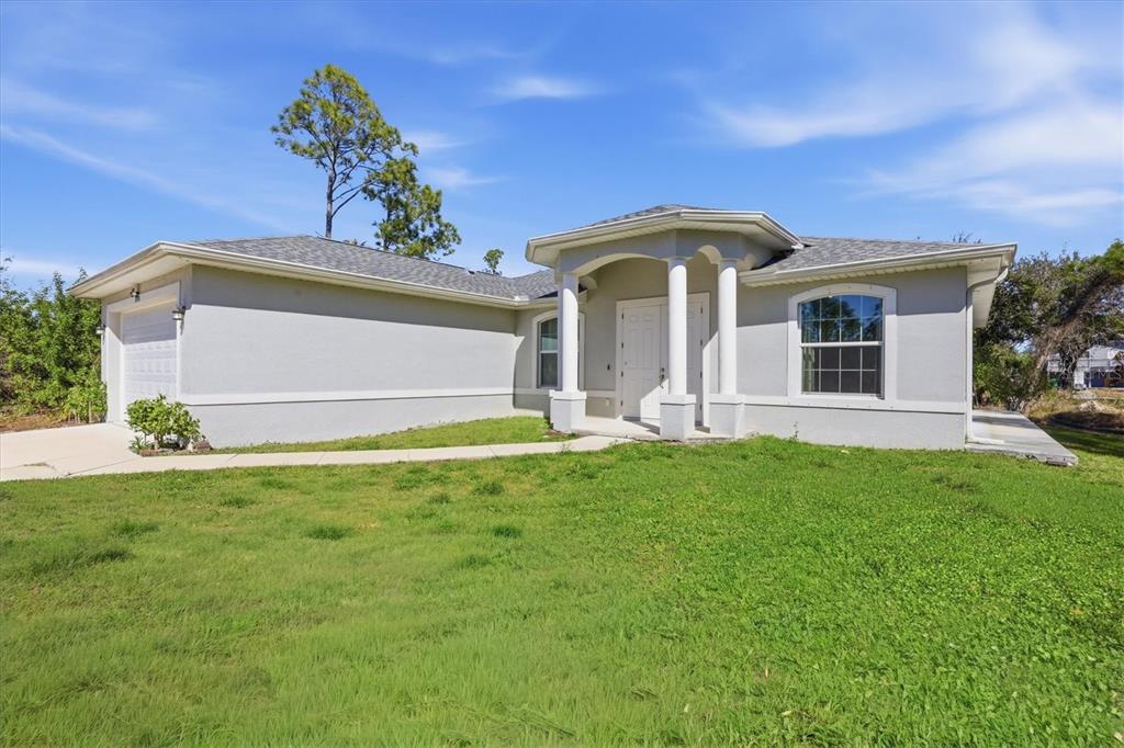 A single-story house with a gray stucco exterior, a two-car garage, and a columned entryway — 3498 DUNKIRK STREET, PUNTA GORDA, FL