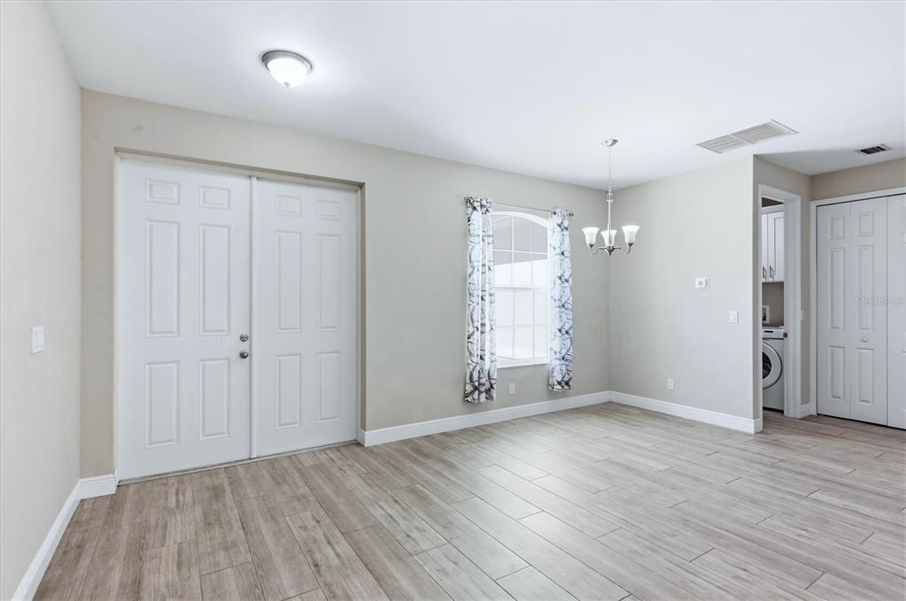 A dining room with light wood-look tile flooring, a chandelier, and double entry doors — 3498 DUNKIRK STREET, PUNTA GORDA, FL