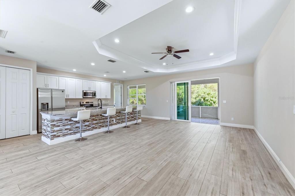 A kitchen with white cabinets and a tiled island opens into a spacious living area — 3498 DUNKIRK STREET, PUNTA GORDA, FL