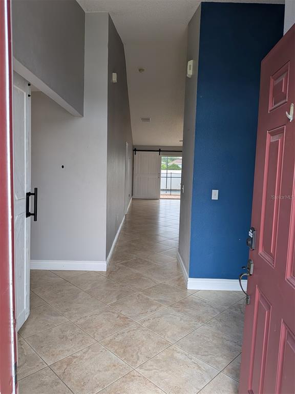 An entryway leads into a hallway with tiled floors, a blue accent wall, and barn doors — 436 BLOOMFIELD DRIVE, KISSIMMEE, FL