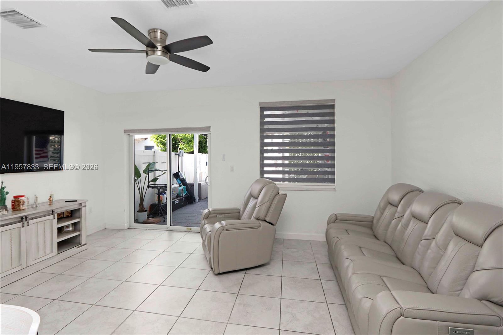 A living room features light tile floors, a ceiling fan, and a sliding glass door — 10628 W 33rd Way, Hialeah FL 33018, HIALEAH, FL