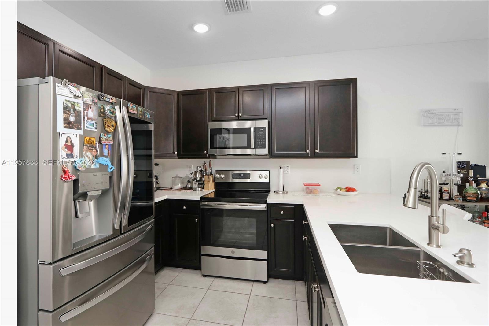 A kitchen features dark wood cabinets, stainless steel appliances, and white countertops — 10628 W 33rd Way, Hialeah FL 33018, HIALEAH, FL