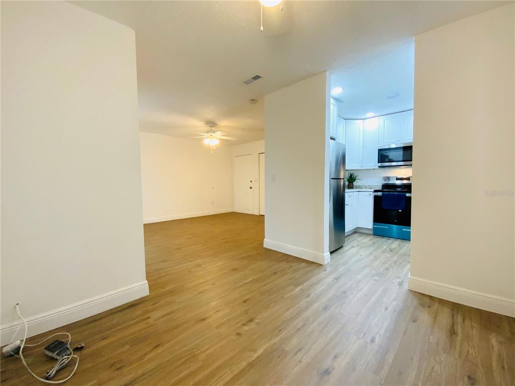 A view from a room looking into a kitchen with stainless steel appliances and flooring — 305 E WELLINGTON COURT UNIT 62, TAMPA, FL