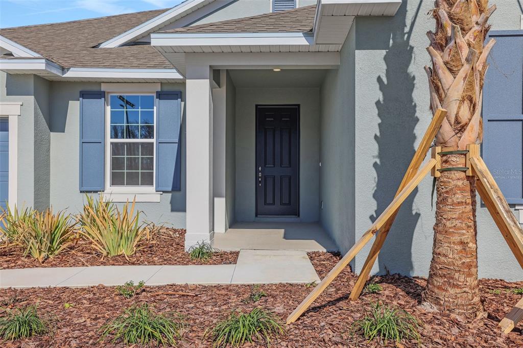 An open-concept living room and kitchen featuring a large sectional sofa and sliding glass doors — 17441 VALLEYWOOD PARKWAY, LAND O LAKES, FL