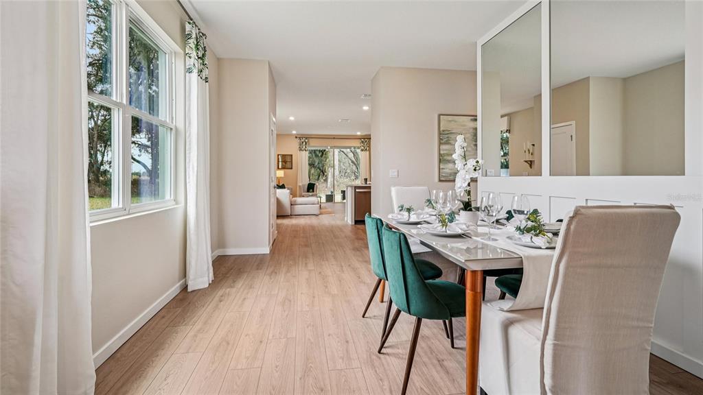 A dining room with wood-look flooring, a glass-top table, and green velvet chairs — 4019 NW 44TH CIRCLE, OCALA, FL