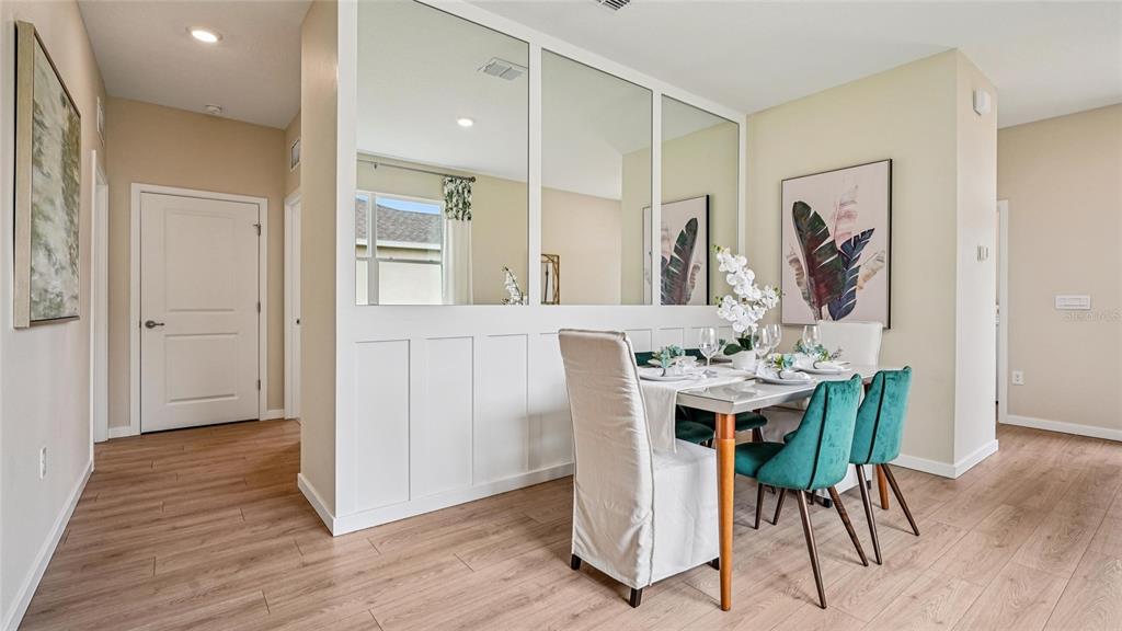 A dining area features a mirrored partition wall, wood-look flooring, and teal upholstered chairs — 4019 NW 44TH CIRCLE, OCALA, FL