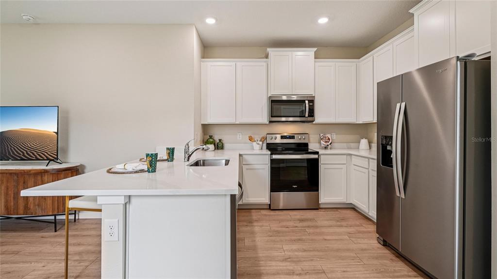 A kitchen features white cabinets, stainless steel appliances, and a large island with a sink — 4019 NW 44TH CIRCLE, OCALA, FL