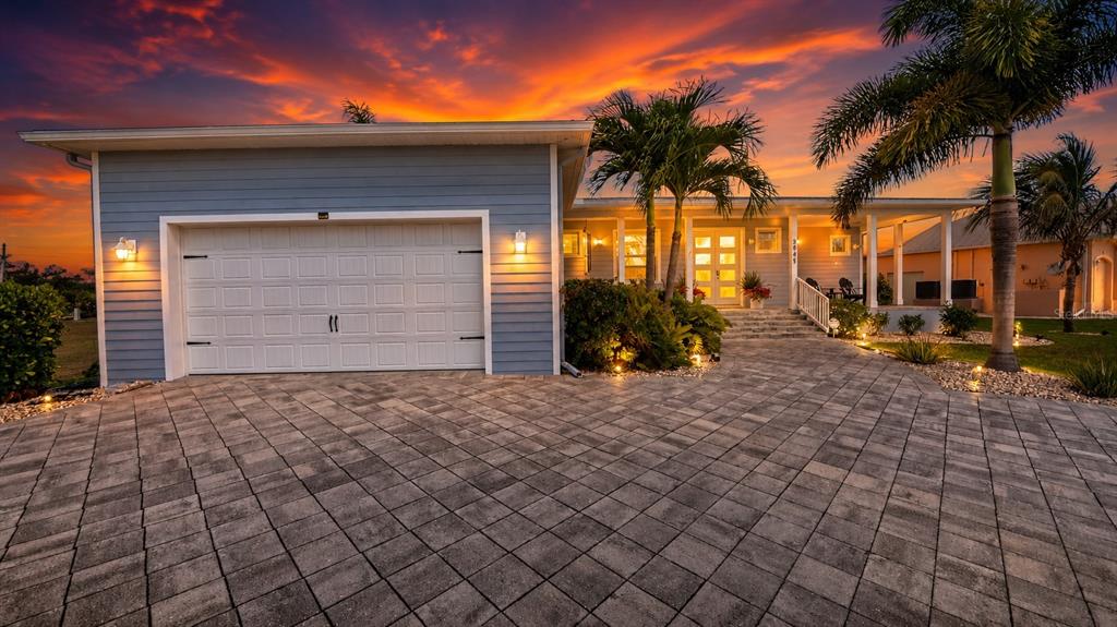 A blue house with a paved driveway and palm trees under a vibrant sunset sky — 3845 BAL HARBOR BOULEVARD, PUNTA GORDA, FL