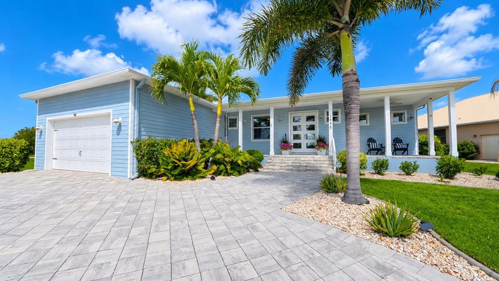 A light blue single-story house features a paved driveway, palm trees, and a covered porch — 3845 BAL HARBOR BOULEVARD, PUNTA GORDA, FL