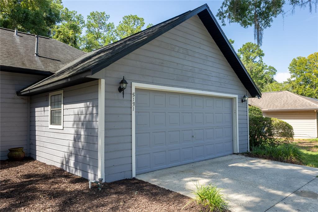 A gray-sided house features a two-car garage with a concrete driveway and dark trim — 5131 NW 35TH PLACE, GAINESVILLE, FL