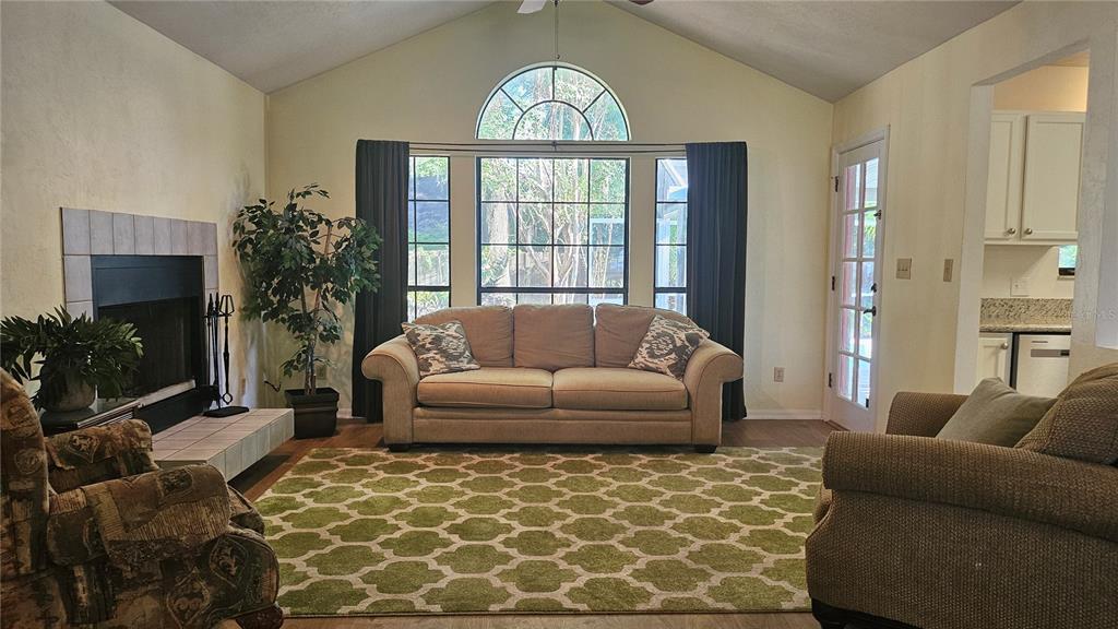 A living room features a vaulted ceiling, a fireplace, a sofa, and a green patterned rug — 5131 NW 35TH PLACE, GAINESVILLE, FL
