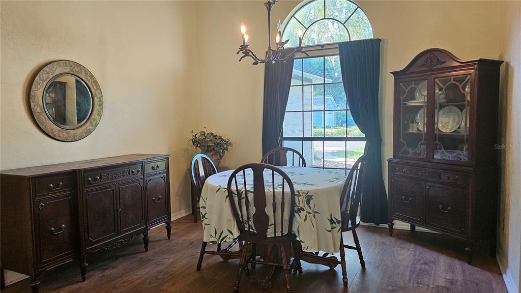 A dining room features a round table, wooden furniture, a chandelier, and a large window — 5131 NW 35TH PLACE, GAINESVILLE, FL