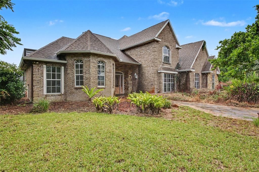A large, two-story brick house with a multi-gabled roof and a stone walkway — 19112 ORTEGA STREET, ORLANDO, FL