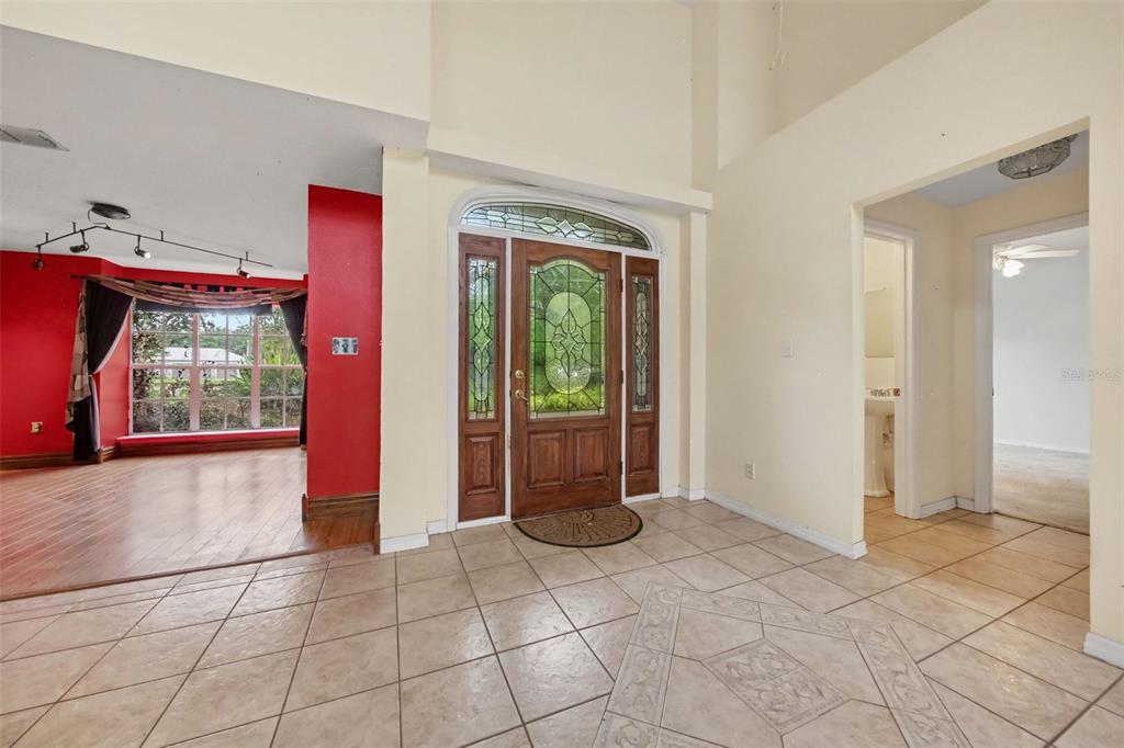 A tiled entryway features a wooden front door with decorative glass and a red-walled room — 19112 ORTEGA STREET, ORLANDO, FL