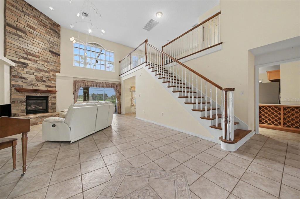 A living room features a stone fireplace, tile flooring, and a staircase with wooden railings — 19112 ORTEGA STREET, ORLANDO, FL